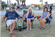 three adults sitting in lawn chair