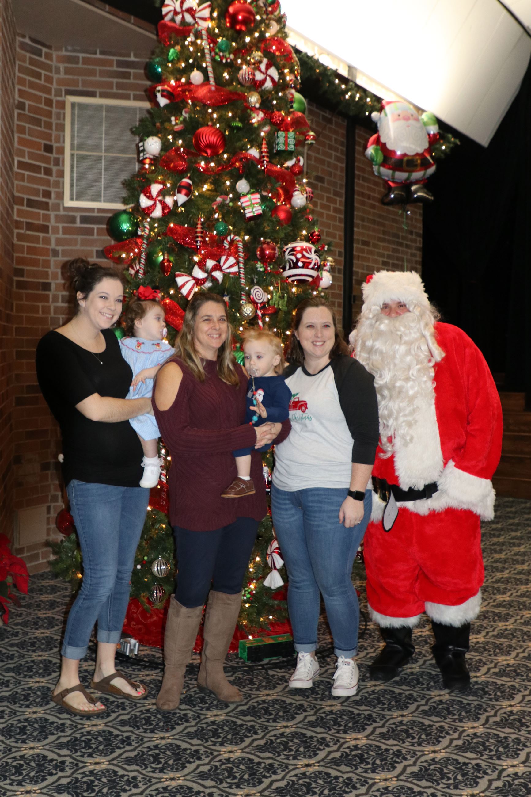 family smiling for photo with Santa