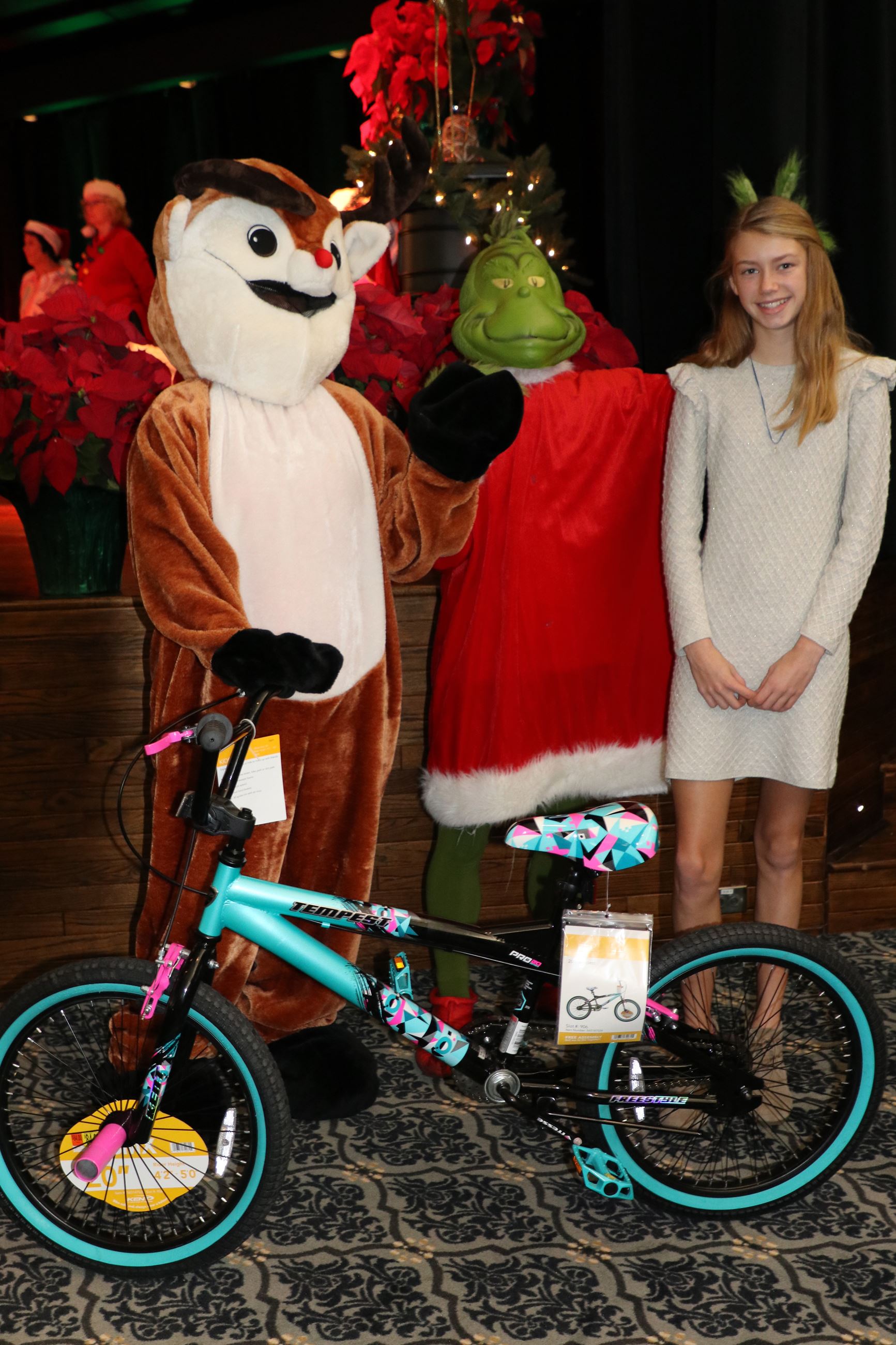 girl standing by new bike with rudolph and the grinch
