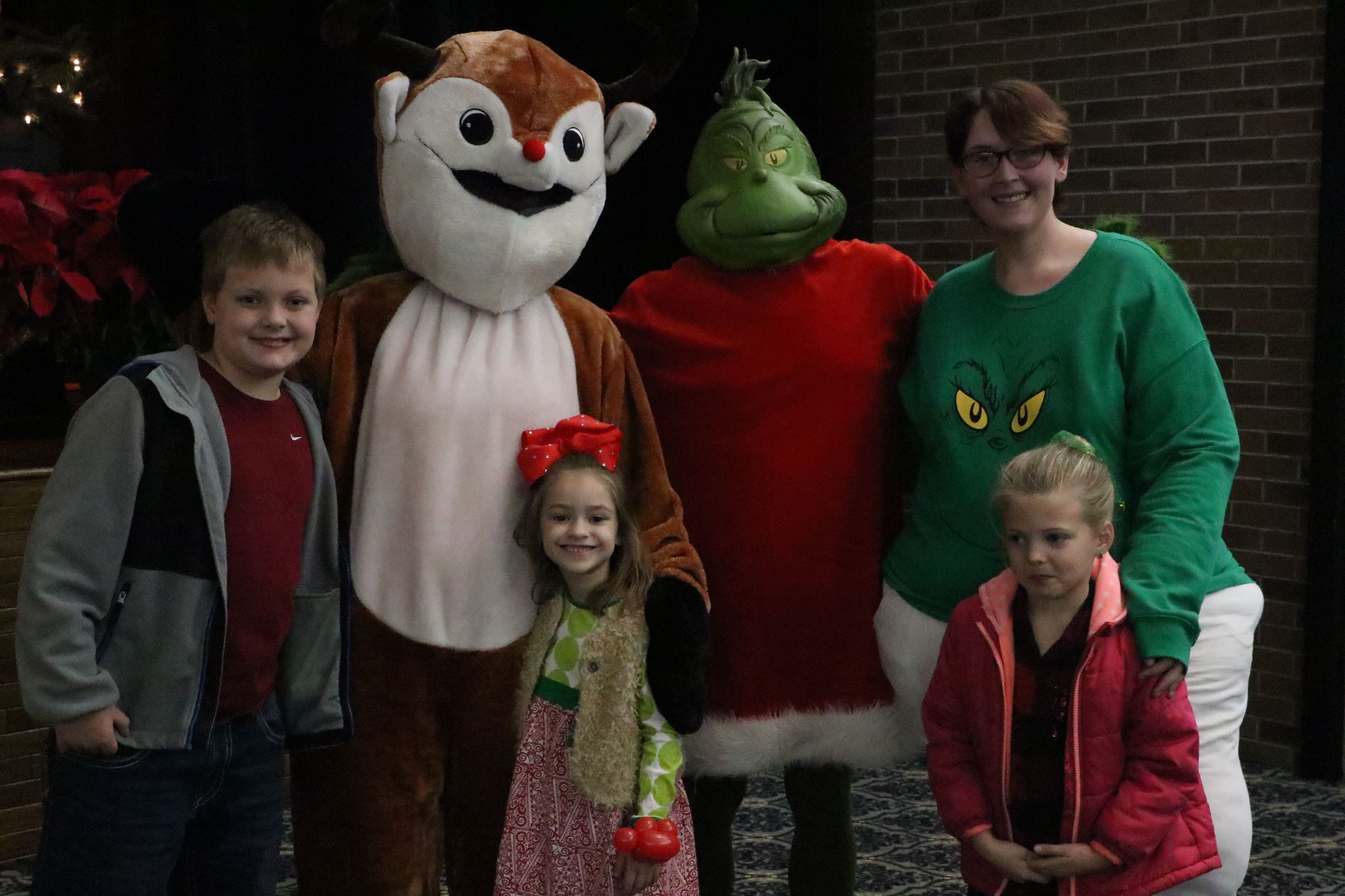 family taking a photo with rudolph and the grinch