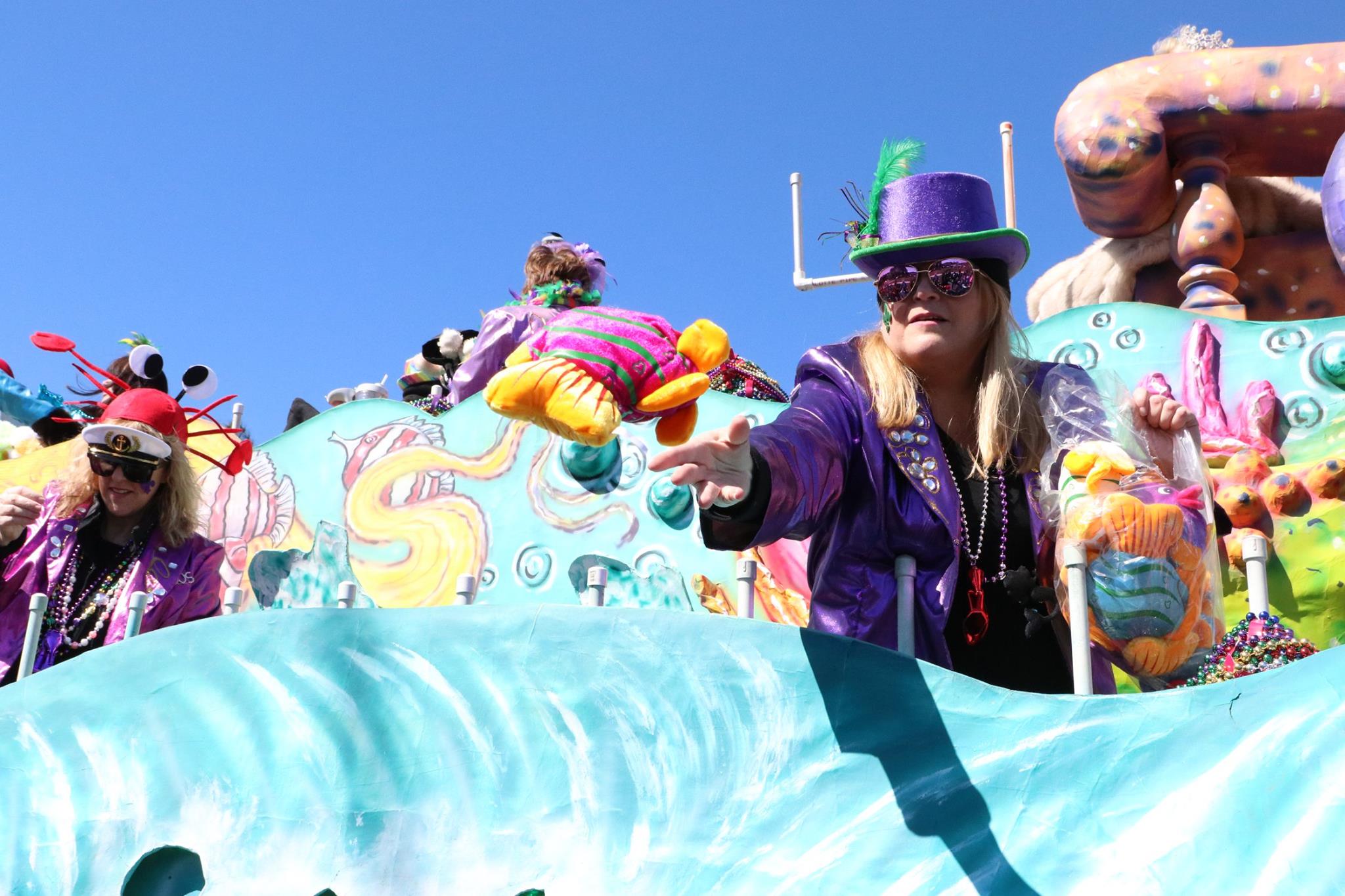 people throwing beads on mardi gras parade float