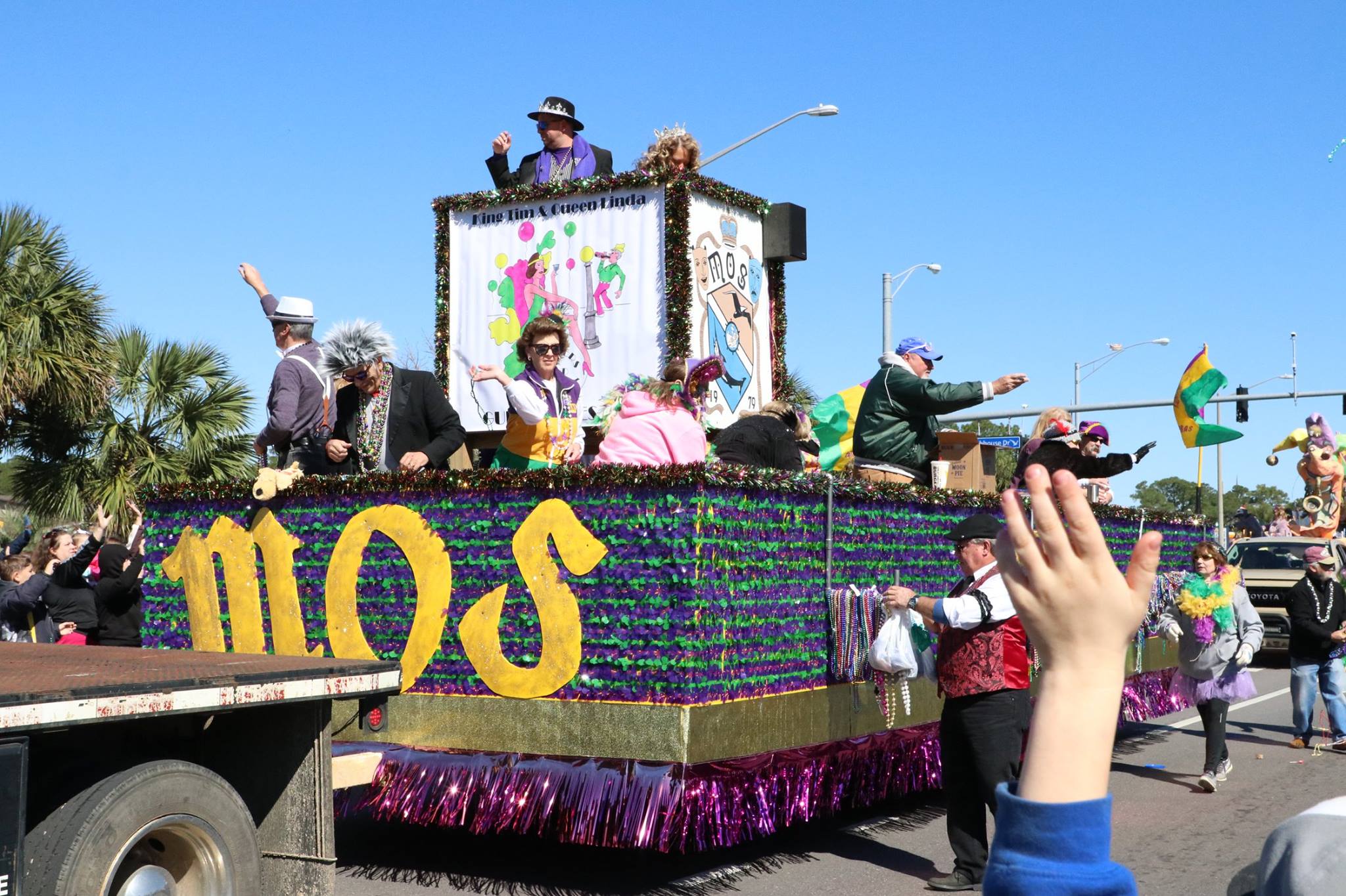 people throwing beads on mardi gras parade float