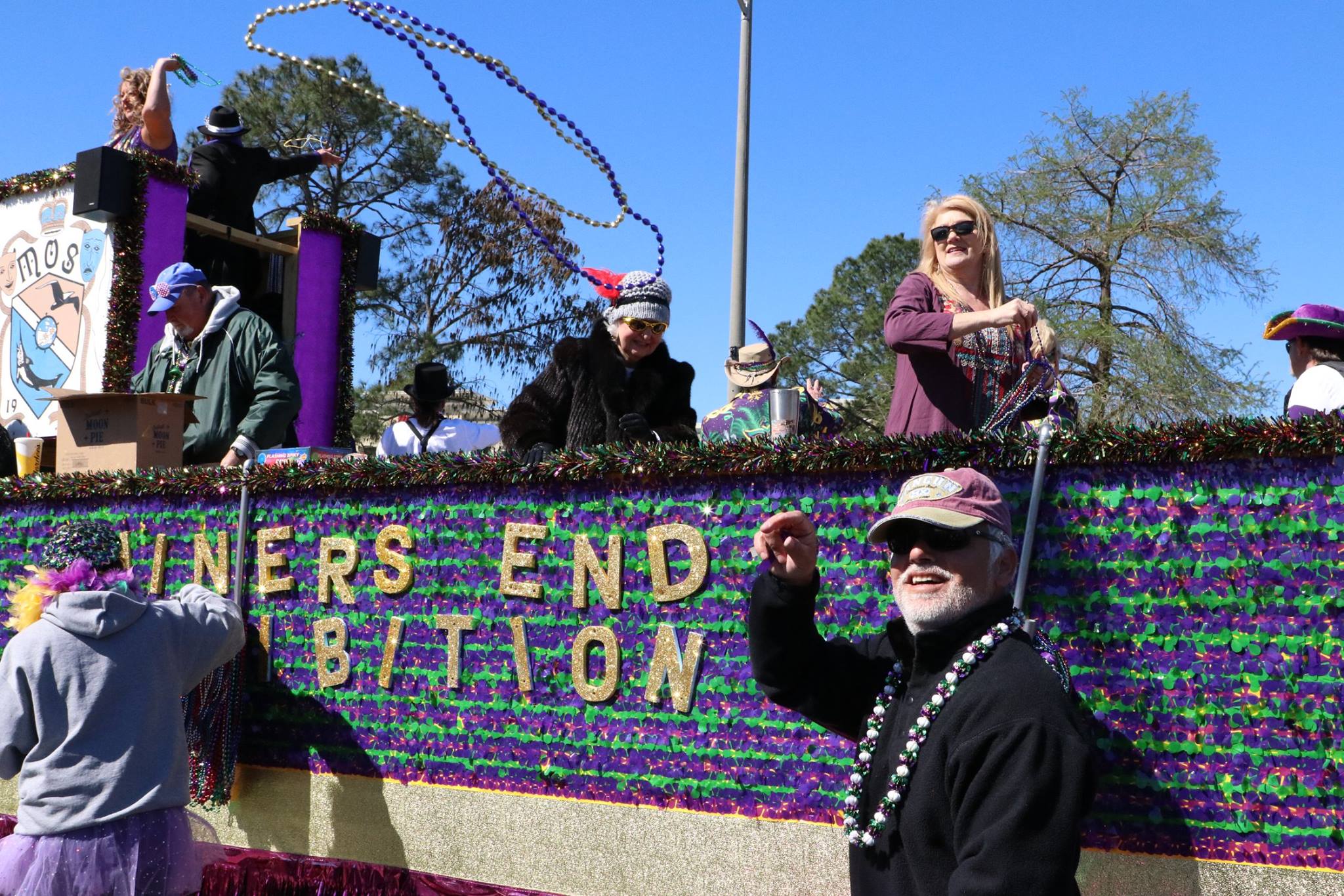 people throwing beads on mardi gras parade float