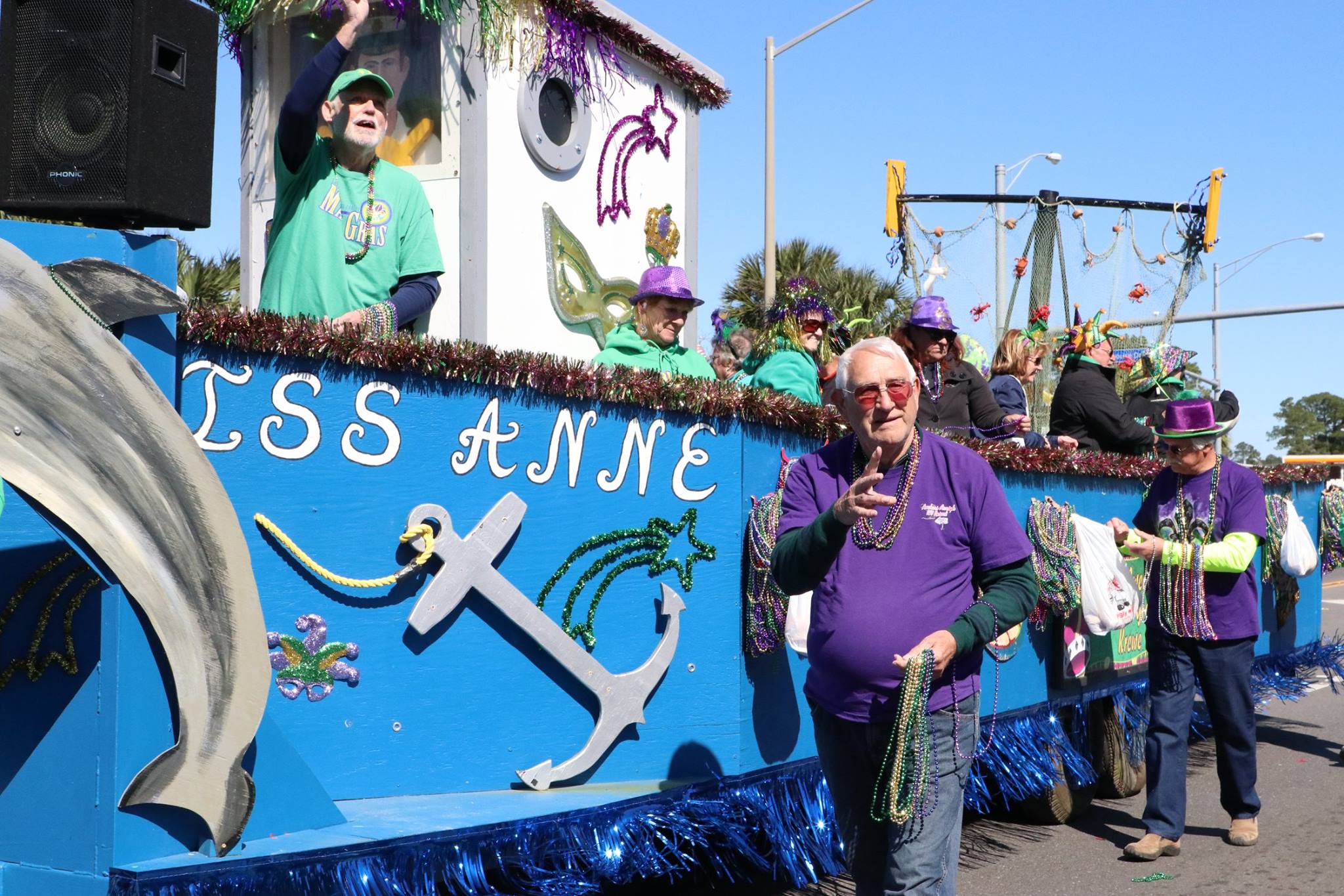 people throwing beads on mardi gras parade float