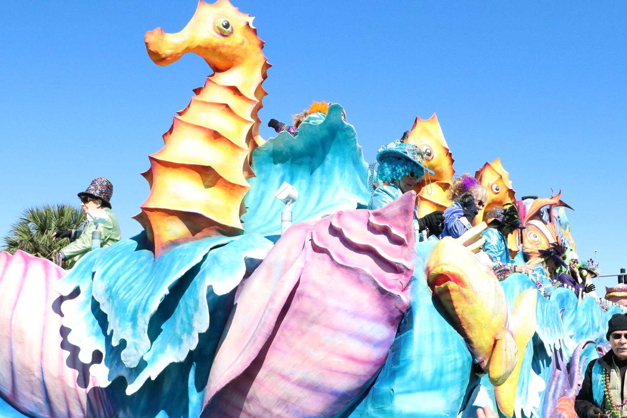 people throwing beads on mardi gras parade float