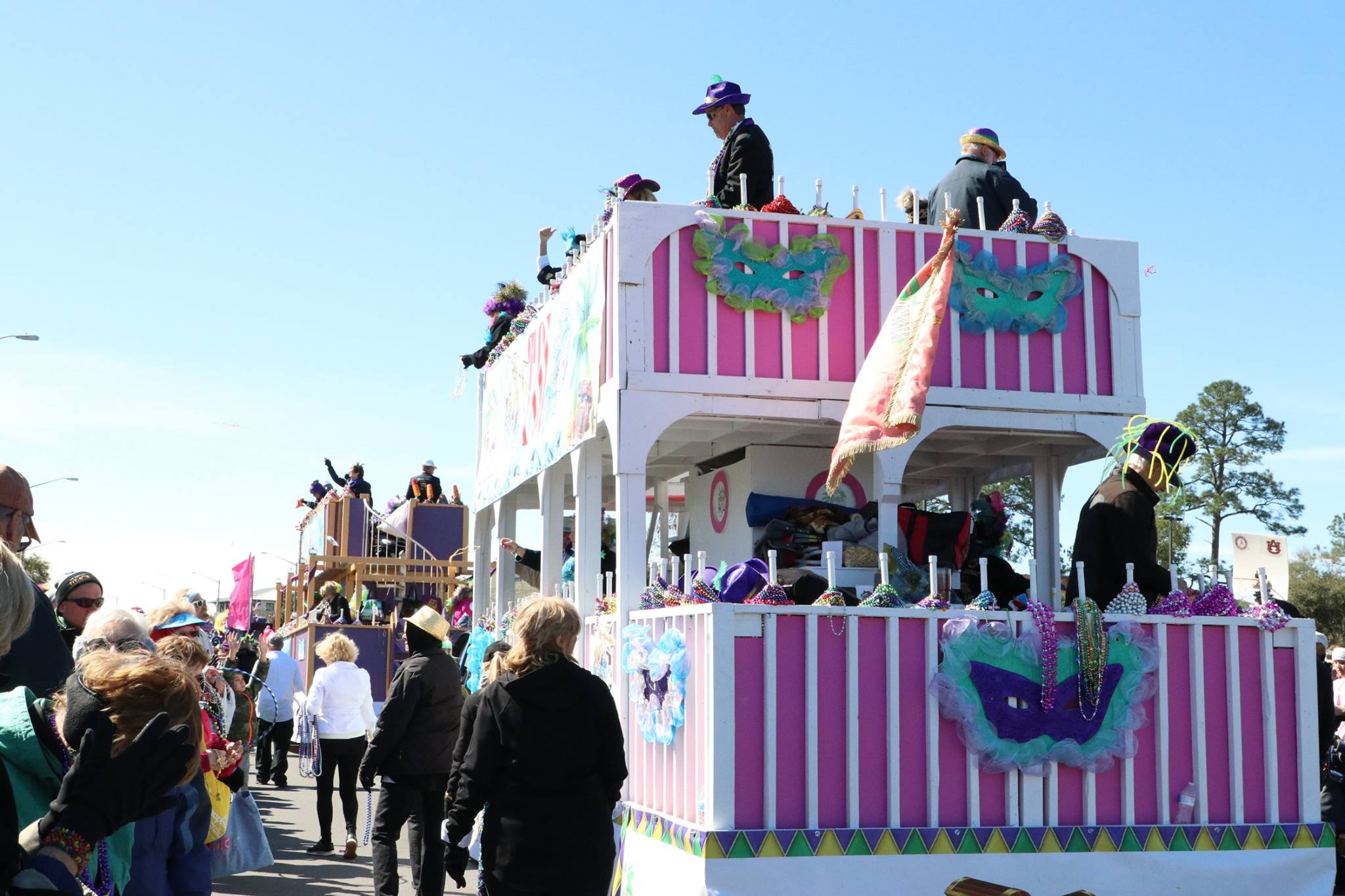 people throwing beads on mardi gras parade float
